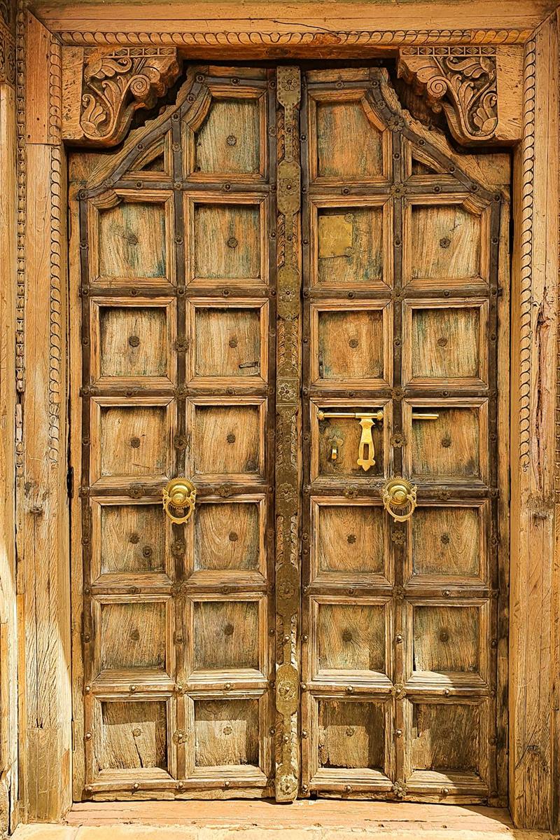 A carved wooden door with brass studs in Lamu Old Town